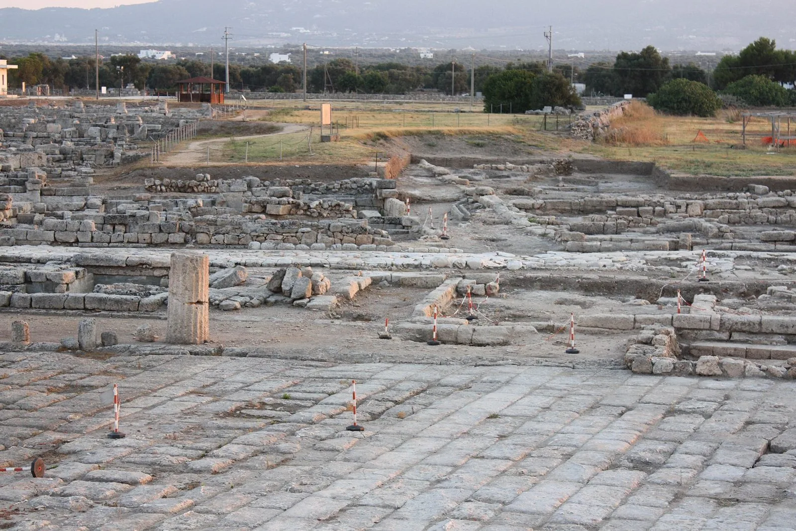 Gli scavi archeologici di Egnazia con il lastricato romano, i resti di muri e una colonna nella luce del tramonto